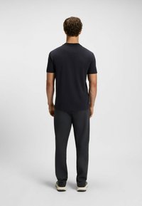 Kurzarm-Navy-T-Shirt mit geripptem Kragen, kombiniert mit dunkelgrauen Hosen und hellen Sneakern. Glattes Material mit lockerer Passform.