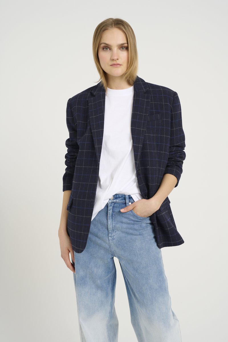 Námořnický kostkovaný blazer s dlouhými rukávy přes bílé tričko, doplněný o světle modré kalhoty s širokými nohavicemi. Měkká textura a přizpůsobený střih.