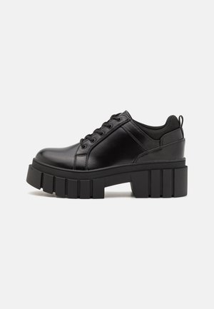 Scarpe platform in pelle nera con tacco a blocco robusto, punta rotonda e design tradizionale con lacci. Presentano una superficie liscia e dettagli minimi.