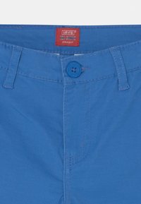 Modré bavlněné chino kalhoty s rovný střih, vybavené zapínáním na knoflík, červenou štítkovou etikou a kontrastními prošívacími detaily.