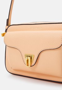 Borsa in pelle color pesca dal design strutturato, con dettaglio di chiusura in oro e bordatura nera. Texture sottile a grana e tracolla removibile.