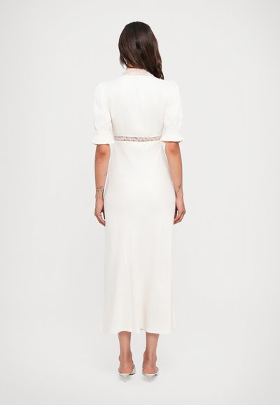 Witte midi-jurk met korte pofmouwen, kantdetails bij de taille en een gladde, lichte stof. Beschikt over een eenvoudige, elegante snit.