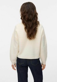 Krämfärgad stickad tröja med ett strukturerat, randigt mönster, ribbade mudd och nederkant. I kombination med mörka denimjeans.