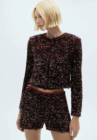 Maroon sequined two-piece outfit featuring a cropped long-sleeve jacket and matching shorts, with black trim outlining the edges.
