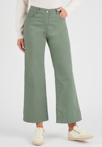 Groene wijde broek van een katoenmix, met een hoge taille, zijzakken en grote manchetten. Gecombineerd met witte sneakers.