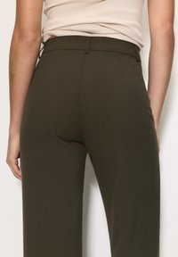 Højtaljede, olivenfarvede bukser lavet af glat stof; har en skræddersyet pasform, struktureret talje og minimale syninger.