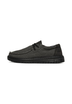 Scarpa casual nera con lacci, tomaia in tessuto strutturato, dettagli cuciti e suola spessa e flessibile su sfondo bianco.