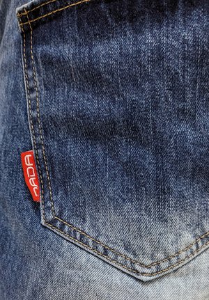 Denim jean pocket with a gradient from dark blue to light blue, featuring a red label and orange stitching along the edges.