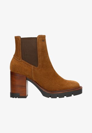 Stivaletto in suede marrone con tacco in legno massiccio marrone, pannelli elastici sui lati e cuciture a contrasto, dotato di punta rotonda e suola texturizzata.