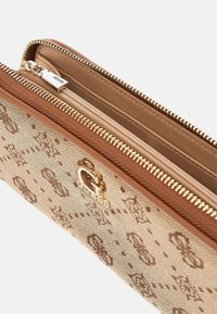 Portafoglio marrone e beige con un esterno testurizzato, zip in metallo dorato e un accento del logo. L'interno è rivestito in tessuto liscio.