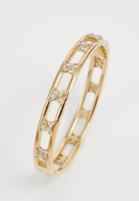 Gouden metalen ring met een uitgesneden ontwerp met stervormige accenten en kleine heldere edelstenen. Gladde afwerking met een gepolijste textuur.