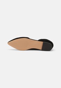 Chaussure plate en daim noir avec un bout pointu et une semelle beige lisse. Dotée d'un petit talon en caoutchouc noir pour la stabilité.