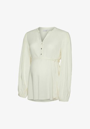 Krema bluzica za nosečnice z dolgimi napihnjenimi rokavi, okroglo izrezom in gumbi kot akcenti. Ima detajl znižanja v pasu za sproščen kroj.