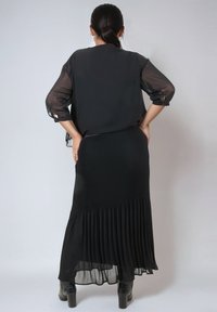 Zwart chiffon blouse met driekwart mouwen, gecombineerd met een geplooide zwarte rok met een uitlopende zoom en een gladde textuur.