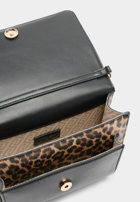 Czarna skórzana torebka o eleganckim wzornictwie. Wnętrze wykończone jest w lamparcie cętki, z teksturowanym detalem na klapie i zapięciem na zatrzask w odcieniu złota.