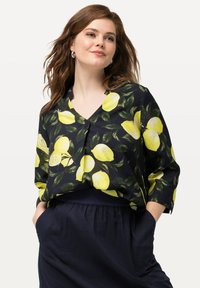 Blusa floreale con scollo a V, in tessuto nero con stampa di limoni gialli e foglie verdi, maniche ¾ e vestibilità comoda. Adatta per l'abbigliamento casual.