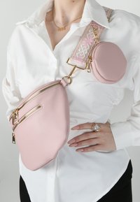 Borsa a tracolla in faux leather rosa con due scomparti con zip, superficie testurizzata e dettagli in oro. Dotata di una tracolla regolabile con motivo.