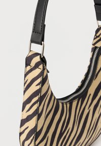 Torebka na ramię z tkaniny w paski zebry, czarnym skórzanym paskiem i widocznym srebrnym suwakiem na jednolitym tle.