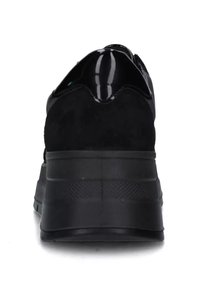 Sneaker in suede nera con un'accattivante finitura in vernice nera lucida sul tallone, suola in gomma testurizzata e finitura liscia. Inclusi elementi di design retrò.