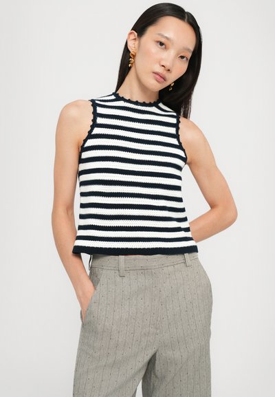 Knit sleeveless top dengan motif garis horizontal navy dan putih, leher scallop, dipadukan dengan celana pinstripe abu-abu muda.