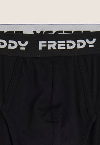 Ropa interior negra con una cintura suave que lleva la palabra "FREDDY" en letras blancas. El material es elástico y liso, sin patrones visibles.