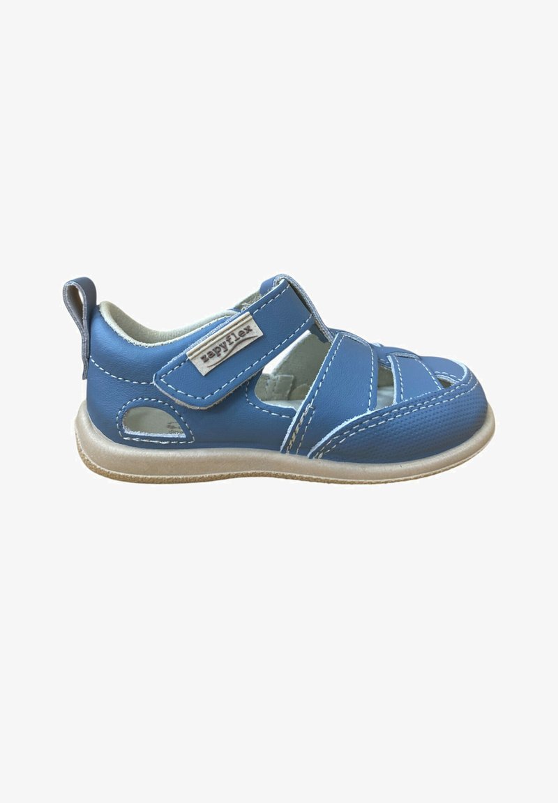 Sandalia infantil azul con puntera cerrada, correa de velcro, costuras blancas y suela beige, diseñada para comodidad y fácil cierre.