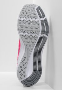 Suola di scarpa Nike con una superficie in gomma grigia a motivo, caratterizzata da una struttura esagonale e a zigzag, arricchita da dettagli laterali bianchi e rosa.