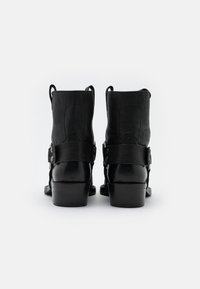 Botas de vaquero de cuero negro con un acabado texturizado, de altura media, que cuentan con una correa con acentos de metal y un tacón cuadrado.