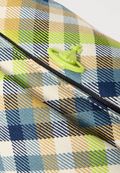 Κοντινή λήψη πολύχρωμου καρό υφάσματος με μπεζ, μπλε, πράσινες και λευκές κλωστές και μικρό πράσινο έμβλημα σε σχήμα σφαίρας με σταυρό στην κορυφή.