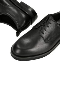 Czarne skórzane wizytowe buty sznurowane, z zaokrąglonymi noskami i grubymi gumowymi podeszwami, pokazane z boku i z góry na białym tle.
