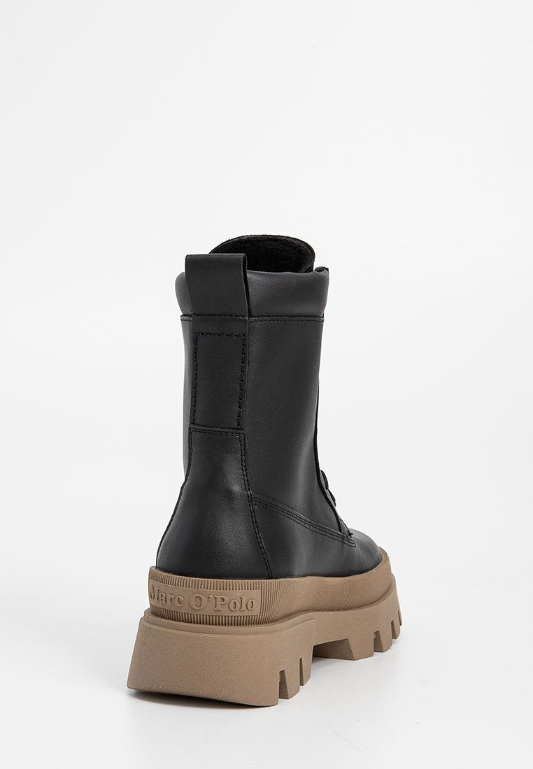Stivale nero in pelle alla caviglia con suola beige spessa e tassellata, marchiato "Marc O'Polo" sul tallone, visto da dietro su sfondo bianco.
