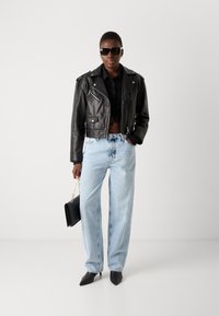 Svart lær cropped bikerjakke, svart skjorte, lyseblå baggy jeans, svarte spisse hæler og svart håndveske med gullkjede.