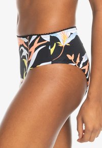 High-waisted bikini bottom in black fabric with colorful floral pattern. Features textured edge detailing and smooth, stretchy material.