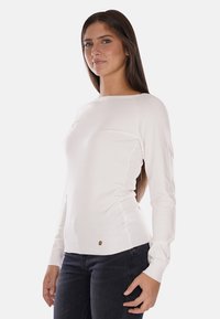 Maglione bianco a maniche lunghe con scollatura rotonda. Presenta un orlo a coste e un piccolo logo vicino alla vita. Texture morbida e liscia.