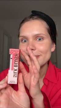 Leppeprodukt i en rektangulær rosa og hvit eske, med fet tekst «SILK BLUSH.» Designet har en klar frontpanel og en metallisk aksent.