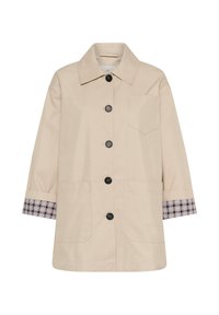 Manteau beige boutonné avec large col, trois poches avant et tissu à carreaux visible aux poignets de manches repliées.