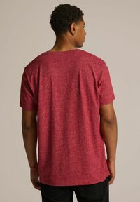 Czerwona koszulka w kropki z okrągłym dekoltem i krótkimi rękawami, charakteryzująca się swobodnym krojem i teksturowanym materiałem zapewniającym oddychalność.