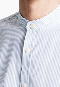 Camicia a righe blu e bianche con colletto, in materiale di cotone, con chiusura a bottoni e bottoni di un leggero colore crema.