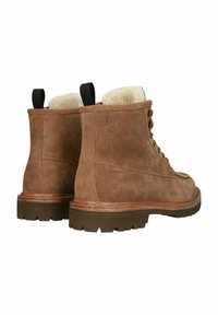 Botas de ante marrón con un interior esponjoso, punta redonda, parte delantera con cordones y suela de goma con relieves para tracción. Tirador negro en la parte posterior.