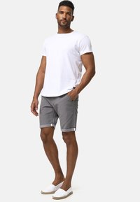 Szare szorty z podwiniętymi brzegami, biała koszulka i białe espadryle. Prosty design, lekki materiał i przednie kieszenie. Neutralne kolory.