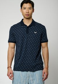 Polo shirt blu navy con un design a pattern, maniche corte e colletto classico. Presenta un piccolo logo ricamato sul petto.