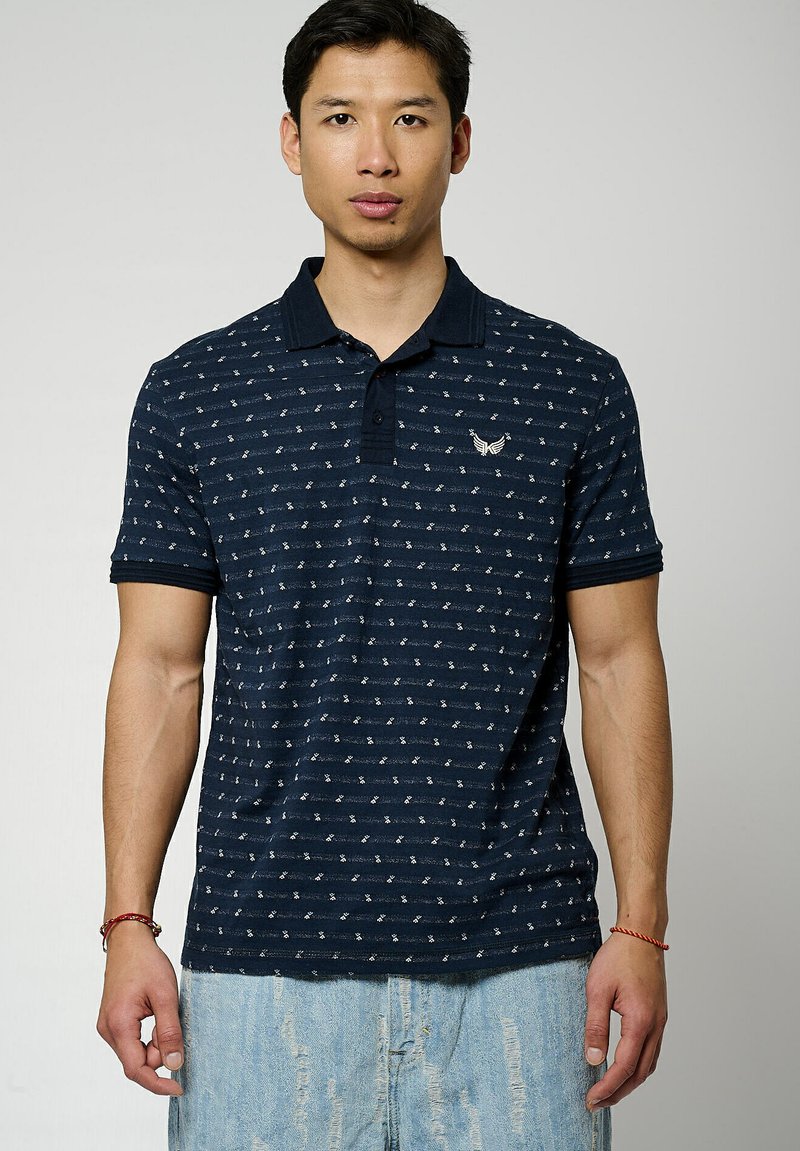 Polo shirt blu navy con un design a pattern, maniche corte e colletto classico. Presenta un piccolo logo ricamato sul petto.