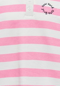 Roosa ja valge triibuline lühikeste varrukatega polosärk, millel on kolm nööpi ja tikitud "New York Cut" logo. Puuvillane materjal, sile tekstuur.