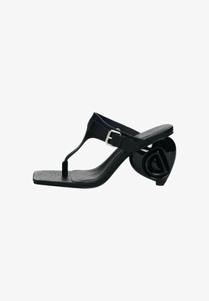 Sandale noire en cuir avec bride à lanière, bout carré, boucle ajustable et talon sculptural arrondi orné d'un motif en "D" en relief.