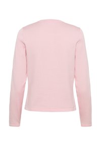 Chemise à manches longues rose clair en tissu doux et texturé. Elle présente un col rond et un ourlet droit avec un design simple et épuré.