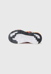 Shoe sole featuring a black rubber base with a patterned grip, white midsole, and vibrant orange, red, and yellow accents along the edges.