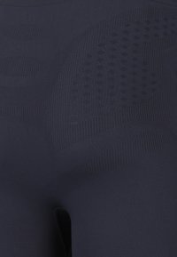 Granatowe legginsy z teksturowanym wzorem o różnej gęstości, gładkim wykończeniu materiału i dopasowanym kroju.