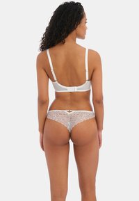 Conjunto de sujetador blanco y bikini de encaje, con tirantes ajustables, cierre de gancho y un intrincado detalle de encaje en la parte posterior del bikini.
