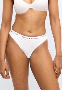 Perizoma bianco in cotone con fascia elastica firmata con la scritta "TOMMY HILFIGER" in nero e dettagli rossi e blu.