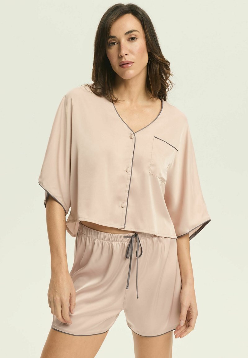 Jasnoróżowy satynowy zestaw do spania składający się z krótkiego topu z dekoltem w kształcie litery V, guzikami i kieszonką na piersi, w komplecie z dopasowanymi szortami na sznurku.